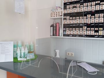 Verkaufstresen in einem Friseursalon mit einem aufgestellten Glasschutz von Wandschutz Nielsen.