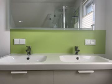 Doppelwaschbecken mit grünem Rückwandpaneel – modernes Baddesign.
