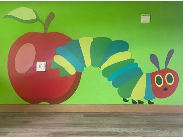 Farbenfrohes Wandbild aus mehreren Wandschutzplatten mit Apfel und Raupe im Stil von 'Die kleine Raupe Nimmersatt', gestaltet für ein Kinderzimmer.