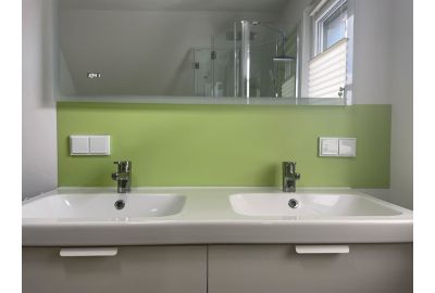 Doppelwaschbecken mit grünem Rückwandpaneel – modernes Baddesign.