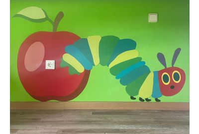 Farbenfrohes Wandbild aus mehreren Wandschutzplatten mit Apfel und Raupe im Stil von 'Die kleine Raupe Nimmersatt', gestaltet für ein Kinderzimmer.